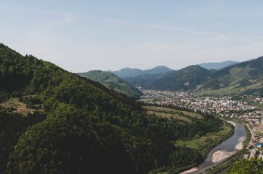 Nehir, kasaba ve gökyüzü ile vadi manzarası yeşil ağaçlarla kaplı dağların arasında
