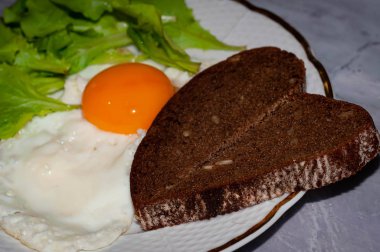 Yağda yumurta proteini ve yumurta sarısı ile lezzetli geleneksel kahvaltı seçici odak, beyaz tabakta duyulmuş ekmek dilimleri ve yeşillik