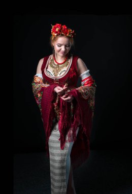 Geleneksel Slav kostümlü, çelenk, yelek, etek, kollar ve siyah üzerine çiçek desenli kolyeli güzel bir dansçı.