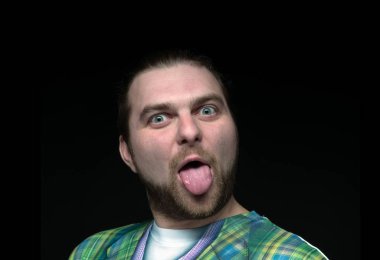 Yakışıklı, şakacı, sakallı, dilinden sarkan ve siyah kameraya bakan eğlenceli bir adam.