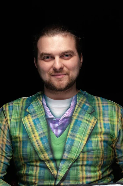 portrait of cheerful handsome stylish bearded man in green checkered blazer looking at camera isolated on black
