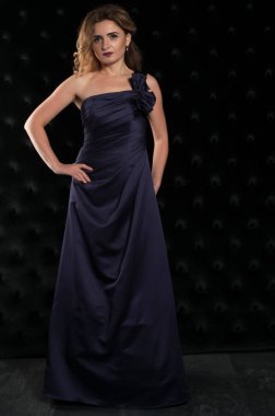 Güzel, kendine güvenen, uzun, mor, çıplak omuzlu, el ele tutuşan ve siyah kameraya bakan bir kadın.