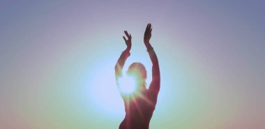 Sıska bir kadının karanlık silueti. Elleri havada güneş ışığıyla aydınlatılıyor. Güneş doğarken Aurora gökyüzünün önünde geleneksel kabile dansı yapıyor.