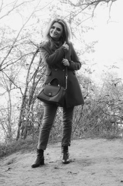 Güz aylarında güzel bir kadının gülümsemesi ve çalıların önünde duruşu.