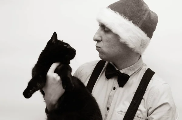 man in Santa hat with a black cat in his arms