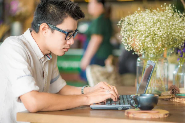 Молодой красивый мужчина использует ноутбук в кафе — стоковое фото