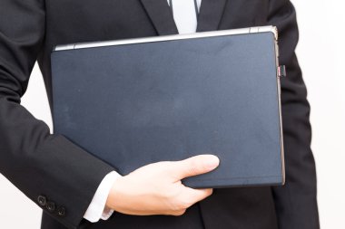 Siyah takım elbise giymiş yakışıklı genç beyaz dizüstü bilgisayar tutun