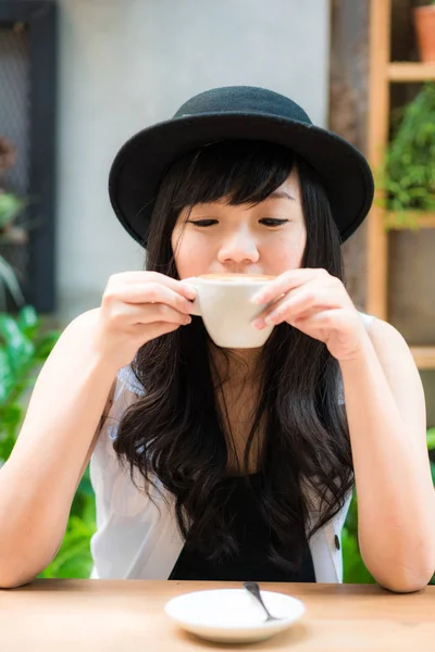 Γυναίκα που κρατά το φλυτζάνι του latte art καφέ στα χέρια της — Φωτογραφία Αρχείου