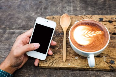 İş adamı el telefon siyah perde ile kahve fincanı üstten görünüm kullanma