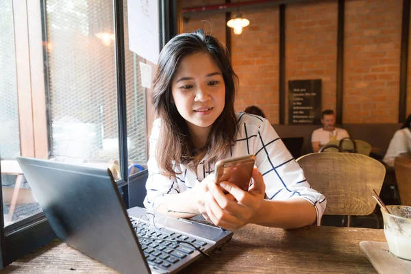 Mujer joven que trabaja en el ordenador portátil mientras está sentado en la cafetería — Foto de Stock