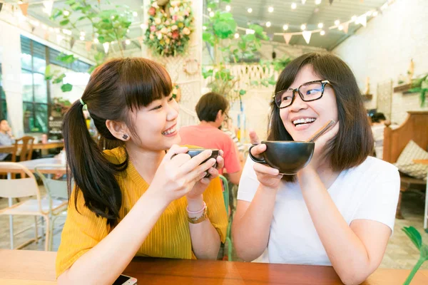 Smiling female asian friends holding coffee mugs while talking b — Stock Photo, Image