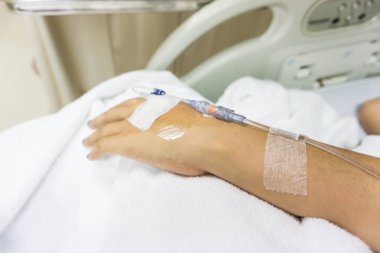 Beyaz battaniyeli hastaya damar yoluyla bulaşan eller.