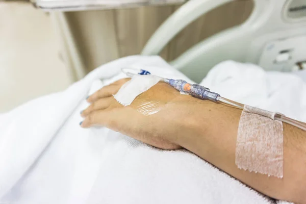 病院のベッドでの患者さんの手に点滴チューブと手のクローズ アップ — ストック写真