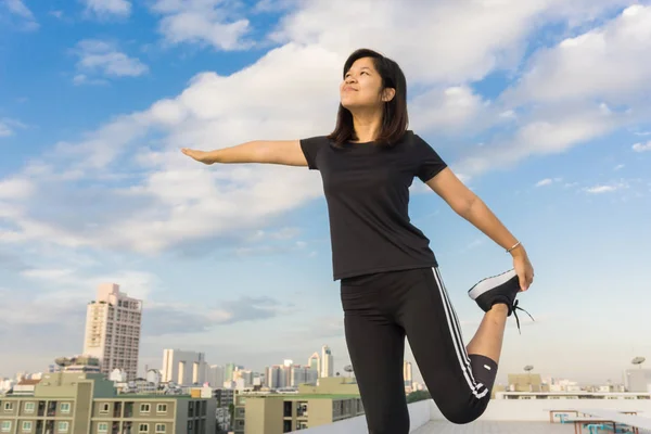 Fitness runner body doing warm-up routine on roof top building b