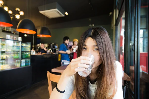 Mujer joven bebiendo un vaso de agua en la cafetería de arte —  Fotos de Stock