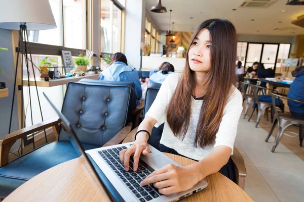 Young smart female student learning on laptop computer in librar — Stock Photo, Image