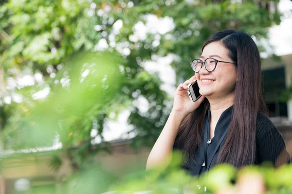 행복 한 아시아 안경 여자 야외 스마트 폰에 대 한 얘기를 사용 하는 여 — 스톡 사진