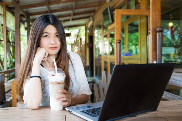 Feliz mujer sonriente trabajando con el ordenador portátil y bebiendo café con leche fría — Foto de Stock