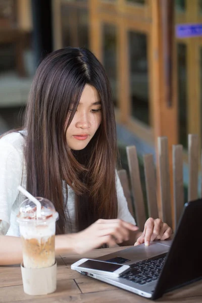 Feliz mujer sonriente trabajando con el ordenador portátil y bebiendo café con leche fría — Foto de Stock