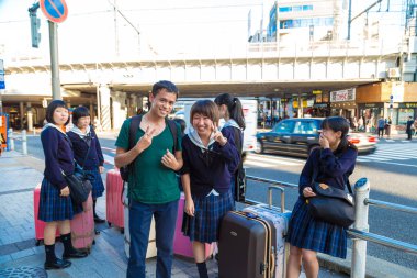 Tokyo, Japonya - 20 Ekim 2016 - güleryüzlü Japon okul kız tokyo seyahat için bagajlı üniformalı grubu
