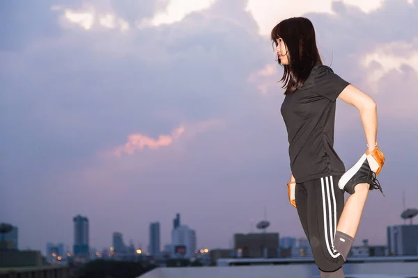 运动服装中的亚洲女性在建筑背景锻炼前伸展身体 — 图库照片