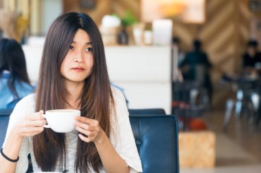 Asyalı kadınlar için bir fikir oluşturmak için Kütüphane fincan kahve ile oturan iş geçmişi kadar kalabalık ile başlayın.