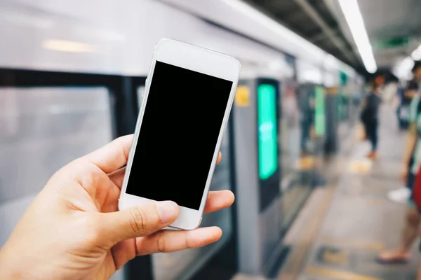 Smartphone black screen in hand at train station blurred people