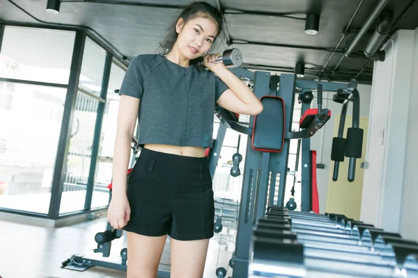 妇女与金属哑铃在现代健身房锻炼 — 图库照片