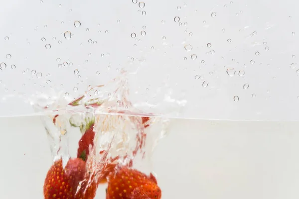 Strawberry fruit splash in water on white background