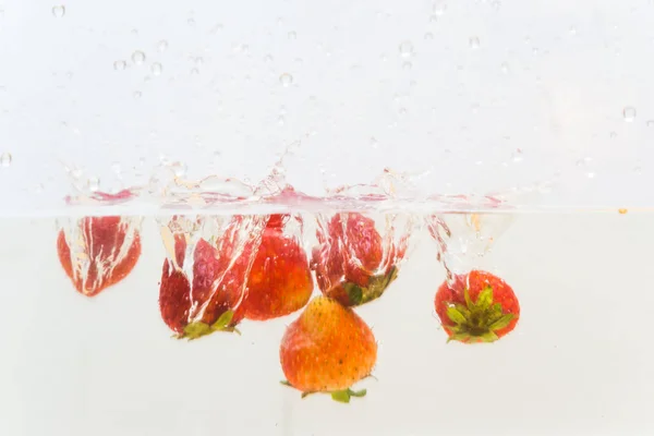 Strawberry fruit splash in water on white background