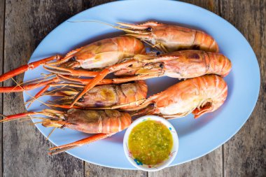 Ahşap tahta üzerinde deniz ürünleri soslu lezzetli nehir karides ateş Yakılan.