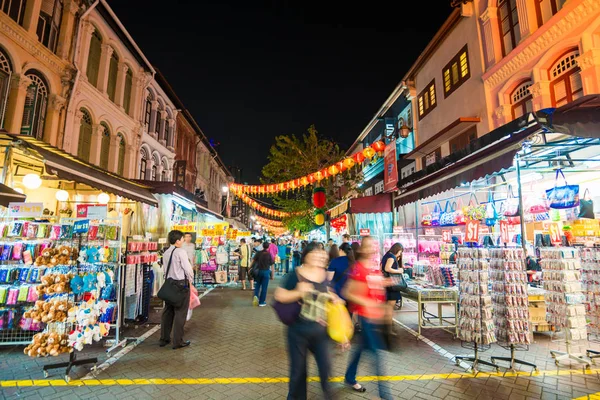 stock image SINGAPORE - MARCH 5: Shoppers walk through a Chinatown market at night on March 5, 2015 in Singapore. The city state's ethnic Chinese began settling in Chinatown circa 1820s.