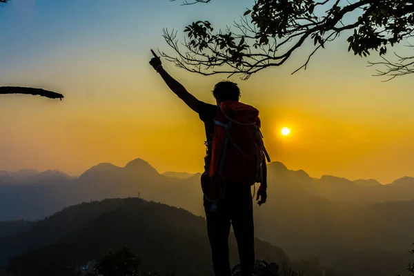 Senderismo hombre de pie en la colina disfrutando de la puesta del sol — Foto de Stock
