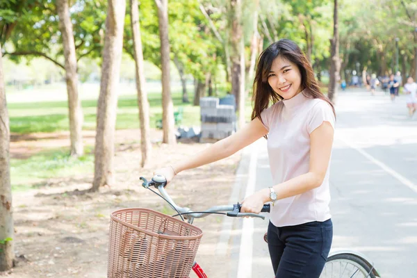 Улыбающиеся здоровые азиатские женщины с велосипедом в парке — стоковое фото