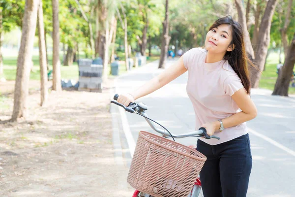 Mosolygó egészséges ázsiai nők kerékpárral a park — Stock Fotó