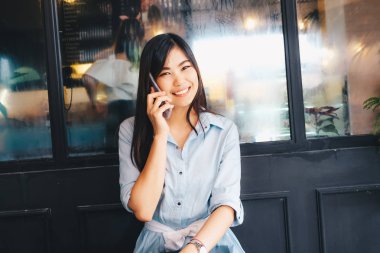 Kafede akıllı telefonda konuşurken gülümseyen kadın