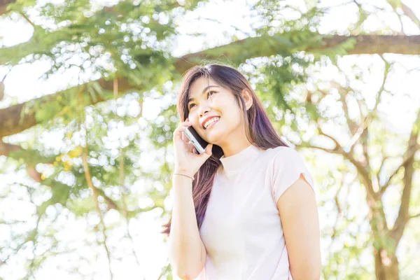 Hermosa mujer asiática usando en el teléfono inteligente con sensación rela —  Fotos de Stock