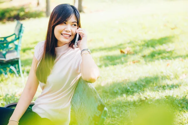 Hermosa mujer asiática usando en el teléfono inteligente con sensación rela —  Fotos de Stock