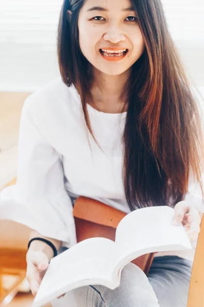 Усміхнені жінки читають книгу на дерев'яному стільці — стокове фото