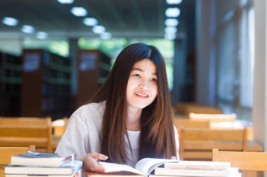 Gülümseyen kadın kitap Kütüphane, eğitim kavramı içinde ahşap sandalye üzerinde okuma