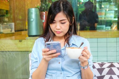 Kahve içmek için vintage kafede otururken cep telefonu kullanarak iş kadınları