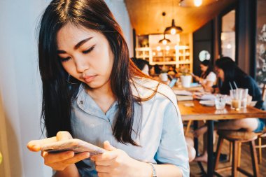 Güzel kadınlar kafede otururken sosyal medya ve oyun oyun için cep telefonu kullanarak
