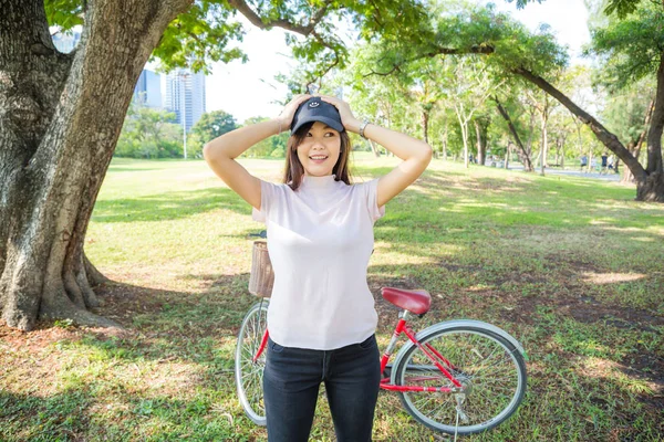 Glad jente med rød sykkel, slapp av i byparken. – stockfoto