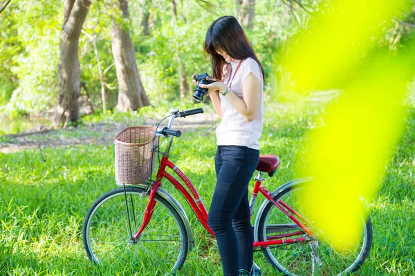 Perempuan dan sepeda dengan kamera mengambil foto dari taman kota alam — Stok Foto