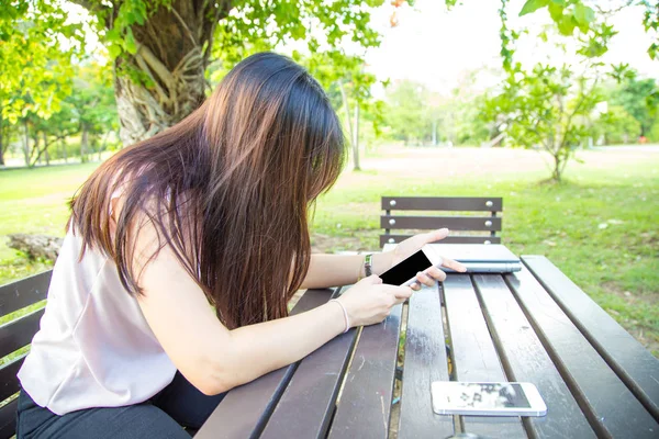 Kobieta siedzi na ławce przy użyciu smartfona w citypark. — Zdjęcie stockowe