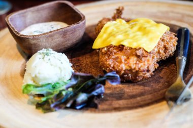 Ahşap tabak üzerinde slive peynirli kızarmış tavuk