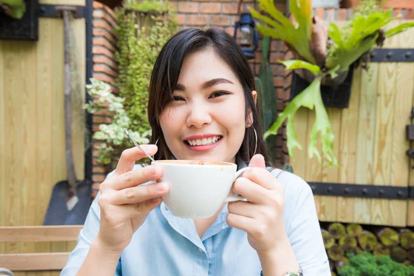 亚洲妇女放松与白色拿铁艺术咖啡杯 妇女在咖啡馆庭院背景 — 图库照片