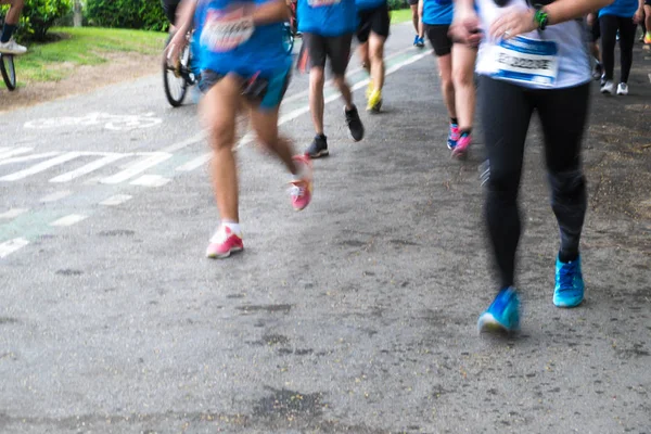 Maratón borroso del movimiento de las piernas corriendo por la carretera — Foto de Stock