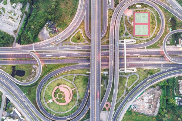 Aerial view of urbal highway intersection road with green exercise background in the morning light