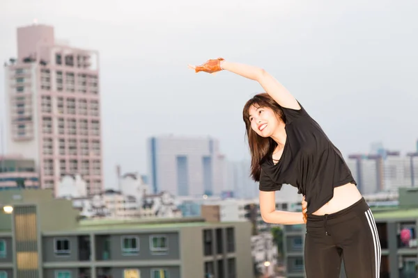 健身妇女运动装束伸展热身工作现代建筑背景 — 图库照片